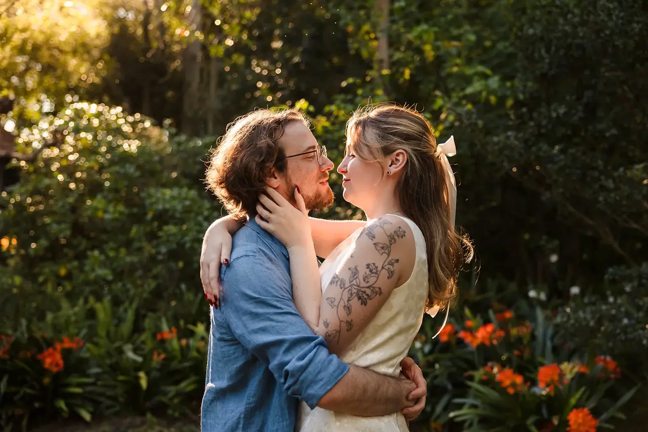 Arden and Kobi in a close embrace among the greenery and orange blooms at Wanneroo Botanic Gardens