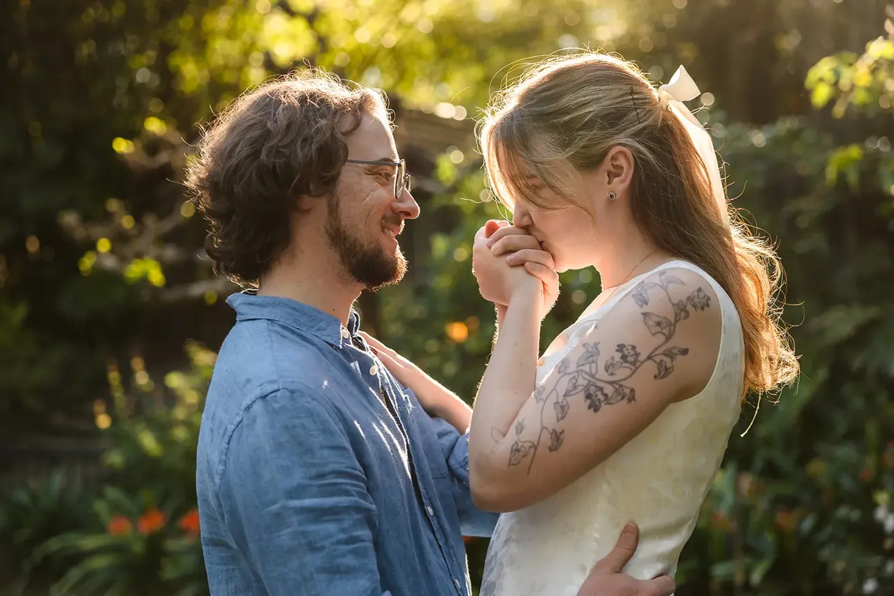 Kobi smiling as Arden kisses his hand in the golden afternoon light at Wanneroo Botanic Gardens