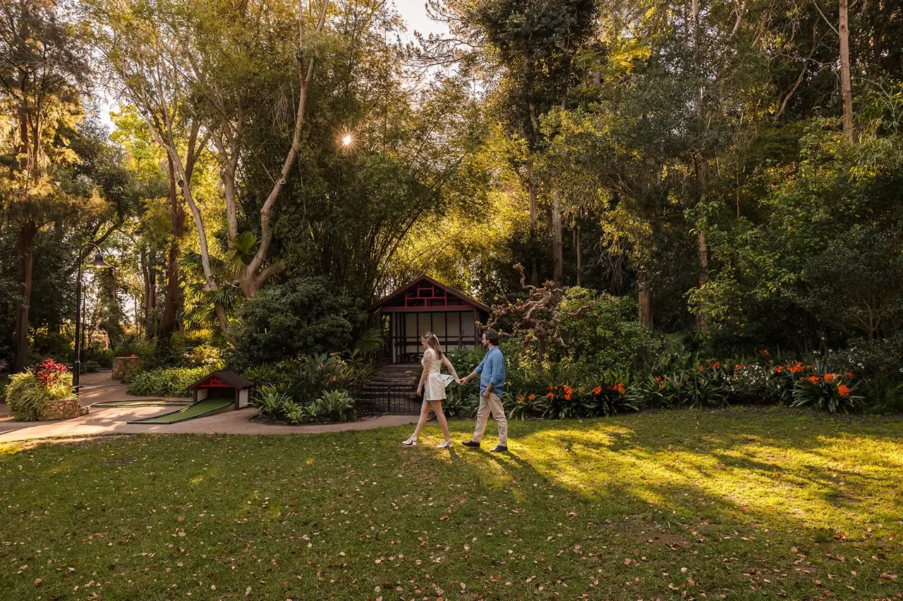 Arden and Kobi walking across the garden lawn in the late afternoon light at Wanneroo Botanic Gardens