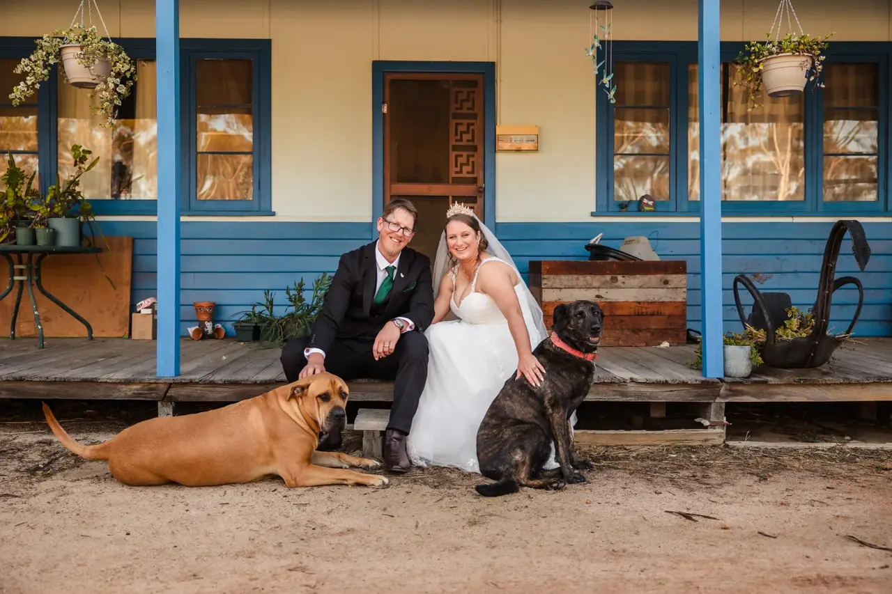 Courtney and Jason on the porch of their farmhouse with their two dogs
