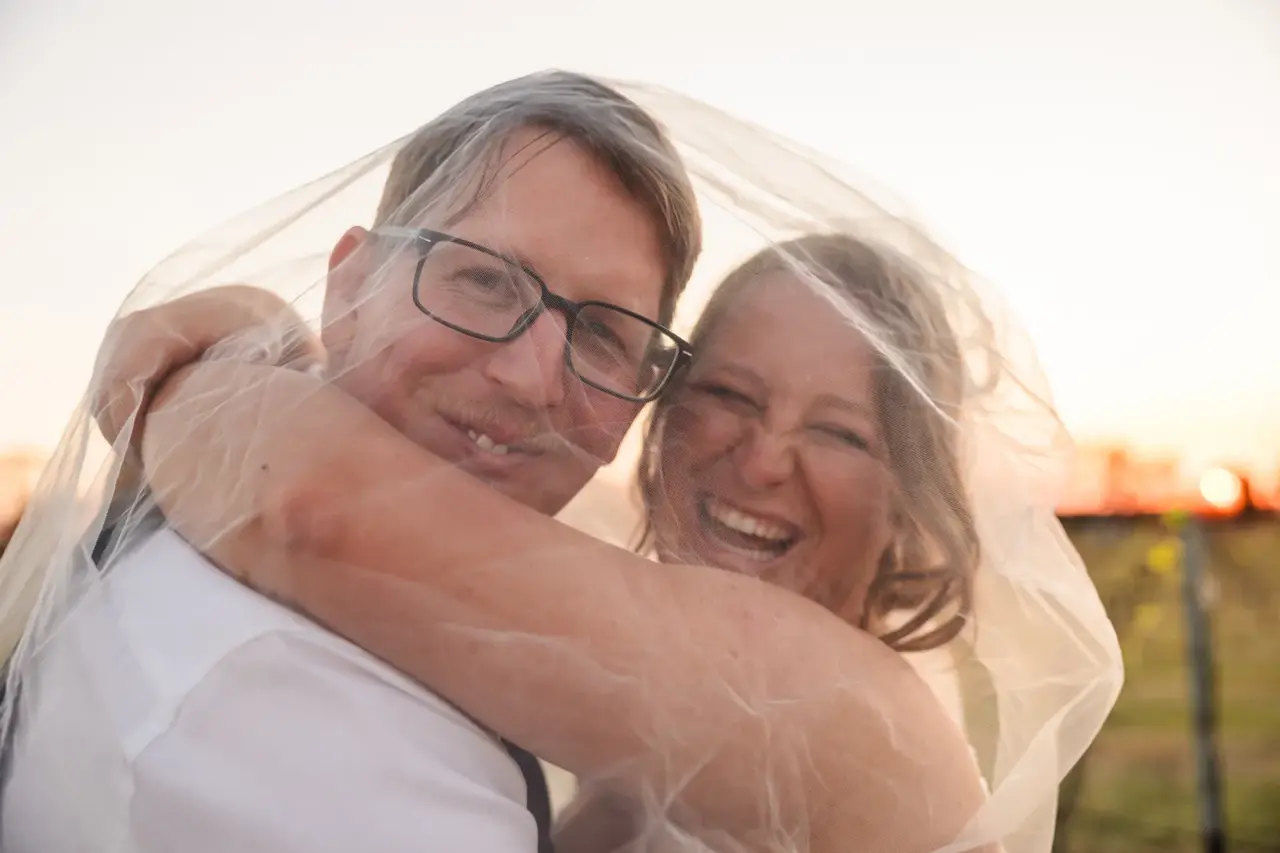 Courtney and Jason wrapped in her veil as the sun sets