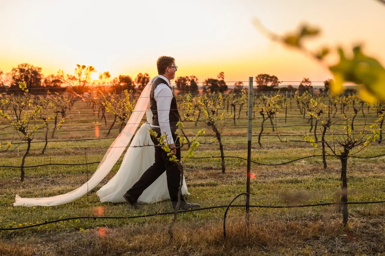 Courtney and Jason walk through the vines at Walkers Hill Vineyard at sunset