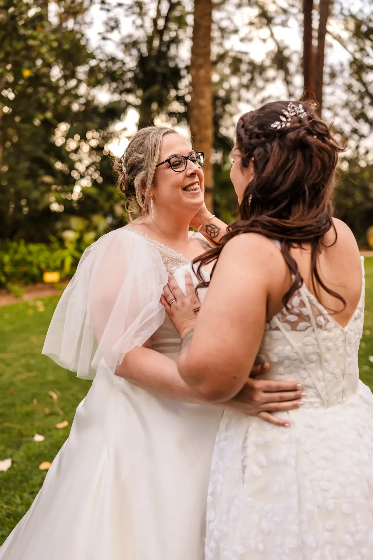 Kat and Jess embracing under a tree in the gardens at Wanneroo Botanic Gardens