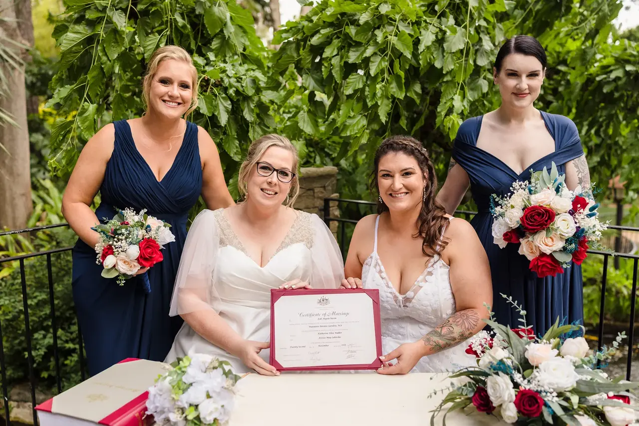 Kat and Jess holding their Certificate of Marriage with their bridesmaids after the ceremony at Wanneroo Botanic Gardens