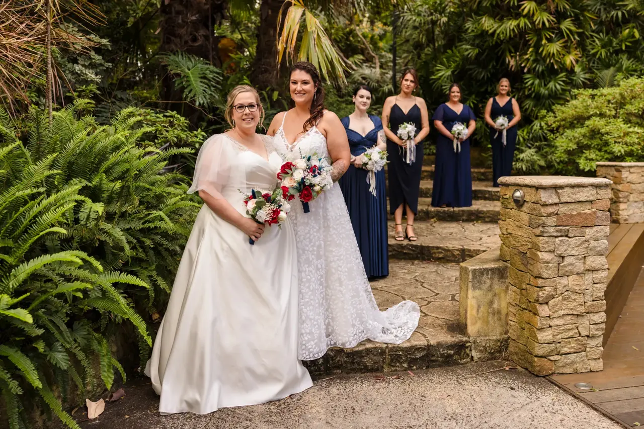 Kat and Jess with their bridal party by the stone wall at Wanneroo Botanic Gardens