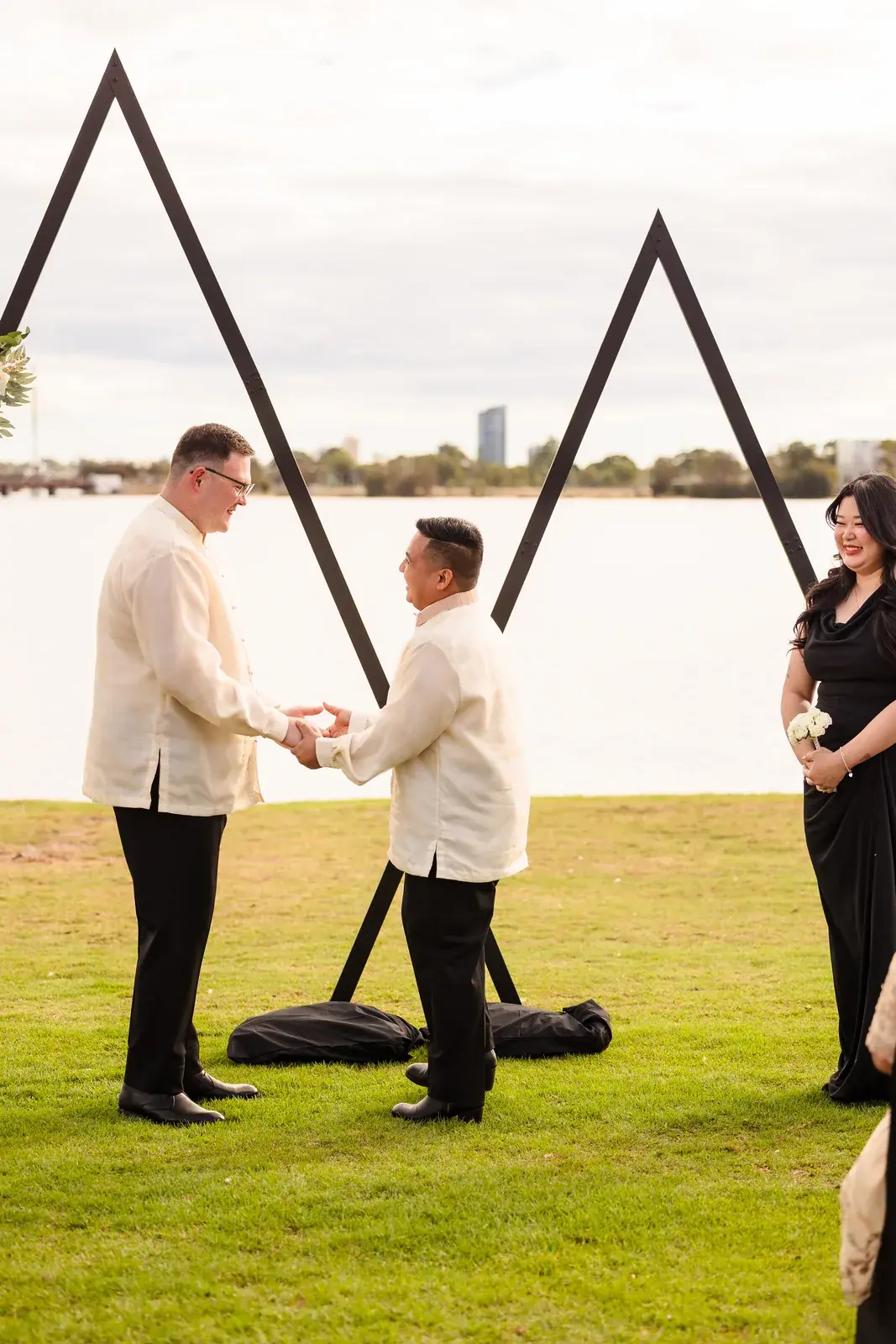 Lloyd and Mitch holding hands at the arbour with the Swan River behind at Burswood on Swan
