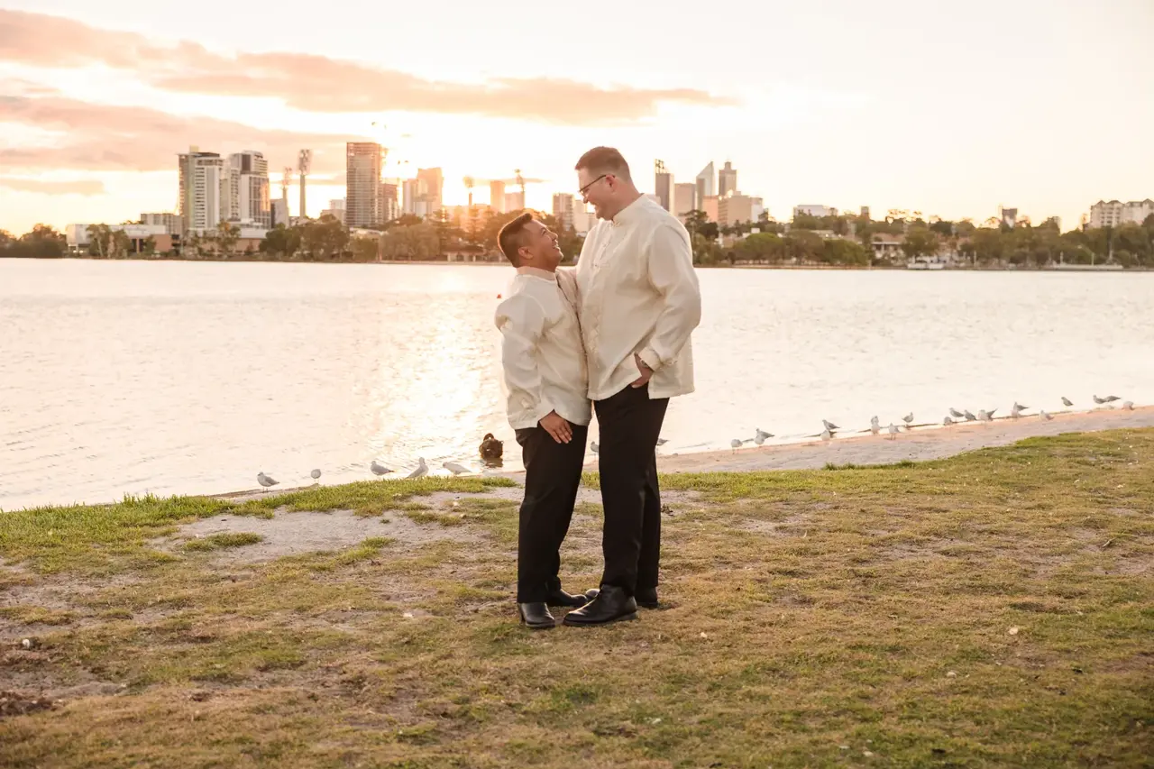 Lloyd and Mitch embracing by the Swan River as the sun sets at Burswood on Swan