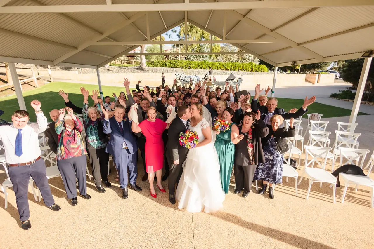Sarah and James kiss while their guests cheer under the big gazebo at Quarry Farm