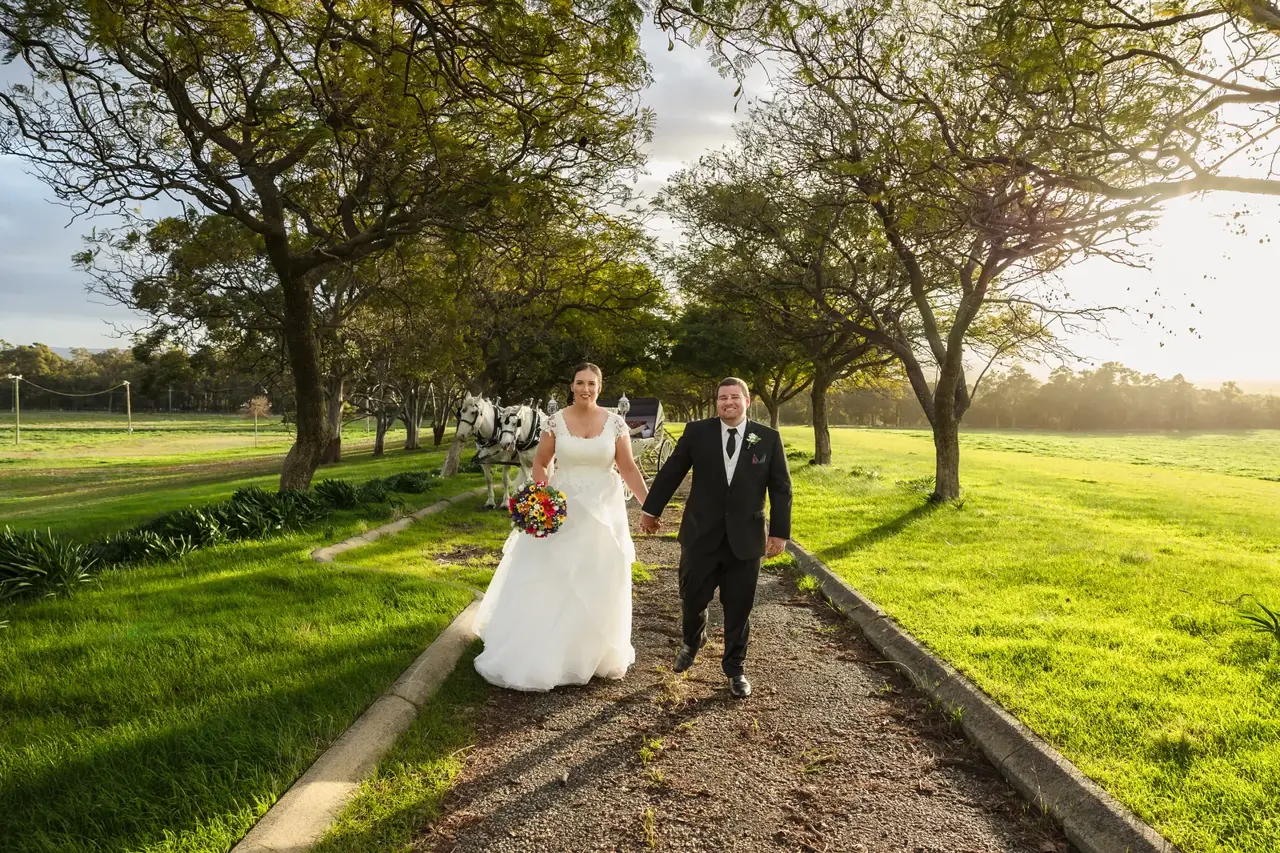 Sarah and James walk hand in hand down the tree-lined driveway at golden hour at Quarry Farm