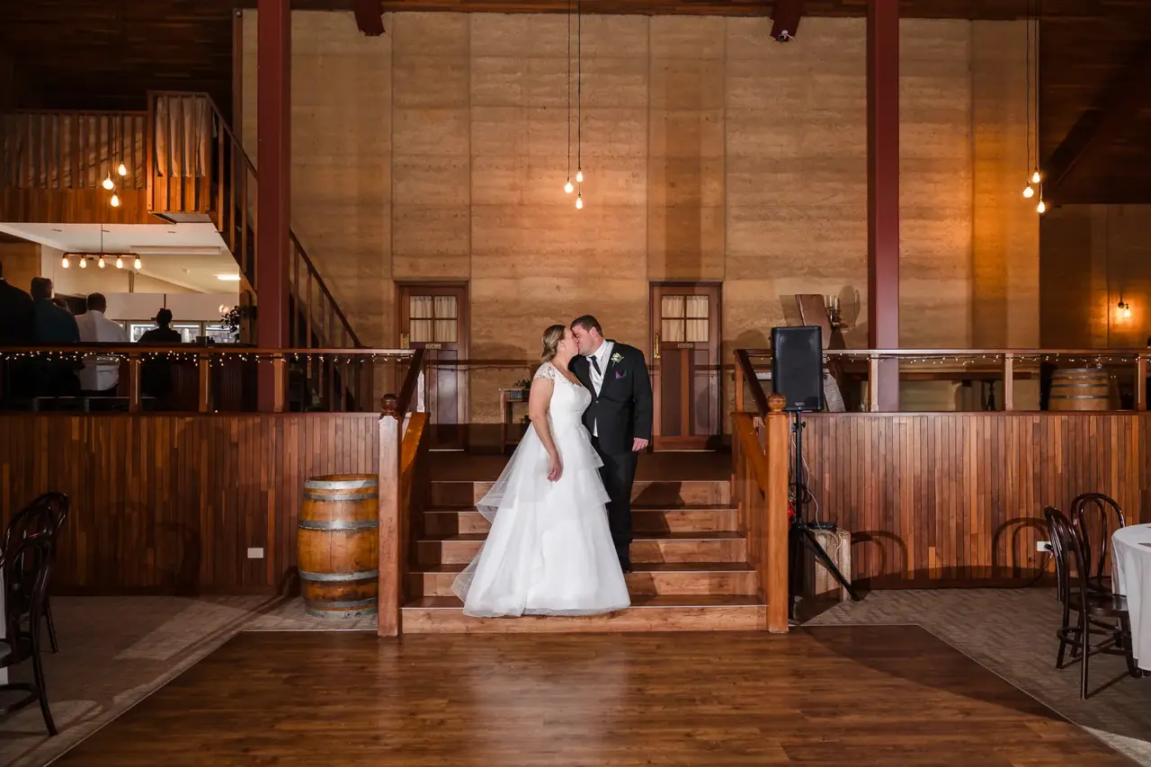 Sarah and James share a quiet kiss by the stairs at their Quarry Farm reception