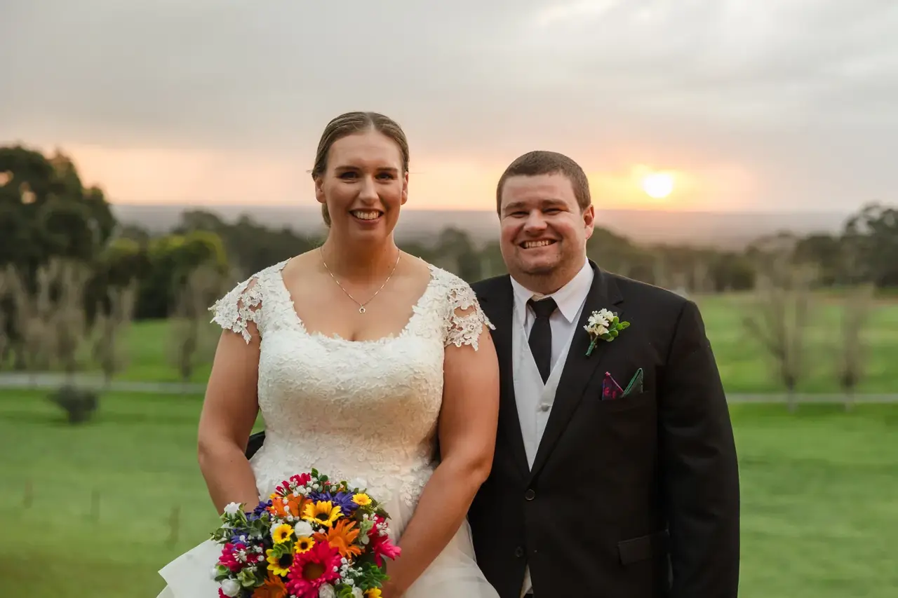 Sarah and James smiling together as the sun sets over the paddocks at Quarry Farm