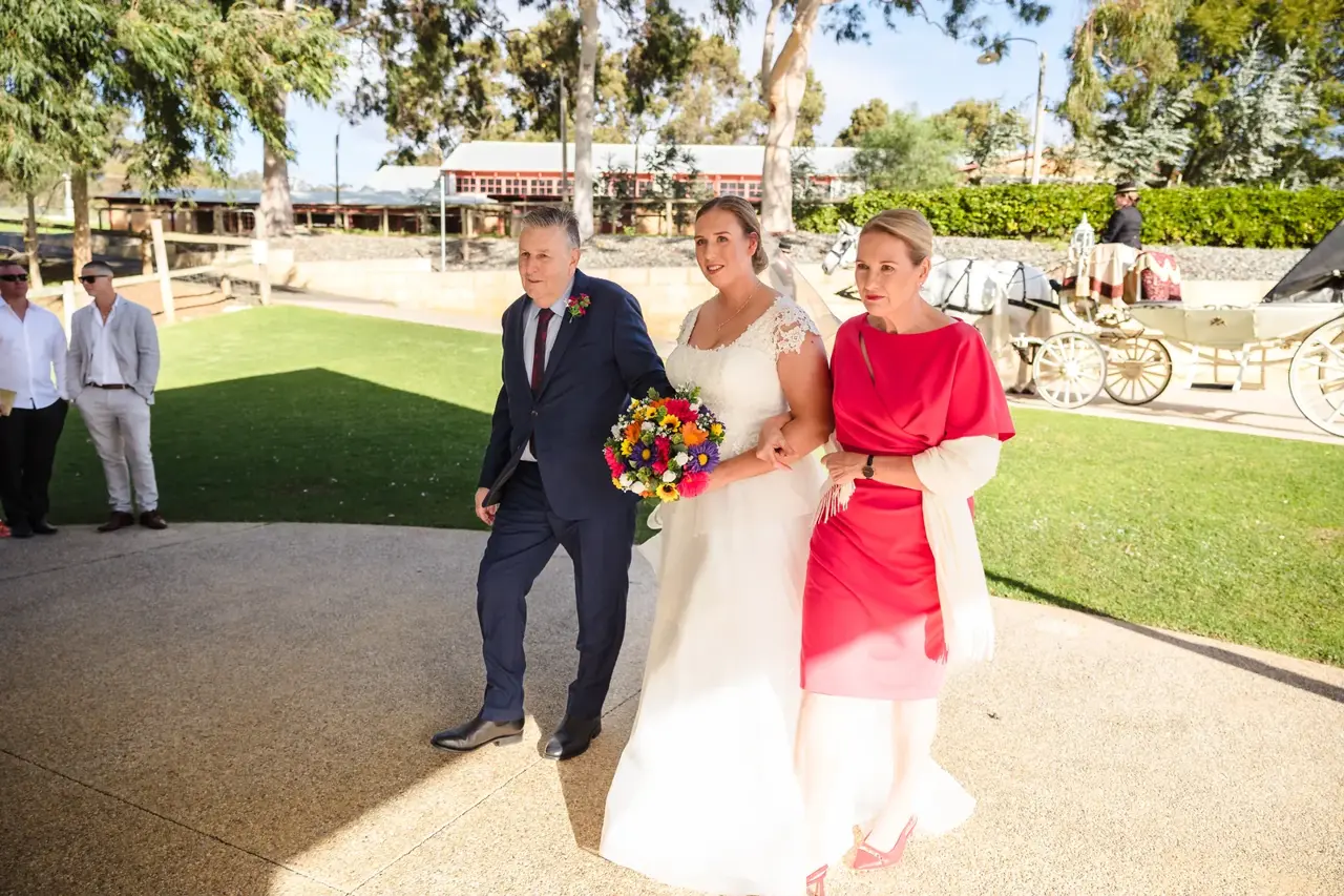 Sarah walks to the ceremony arm in arm with her mum and dad at Quarry Farm