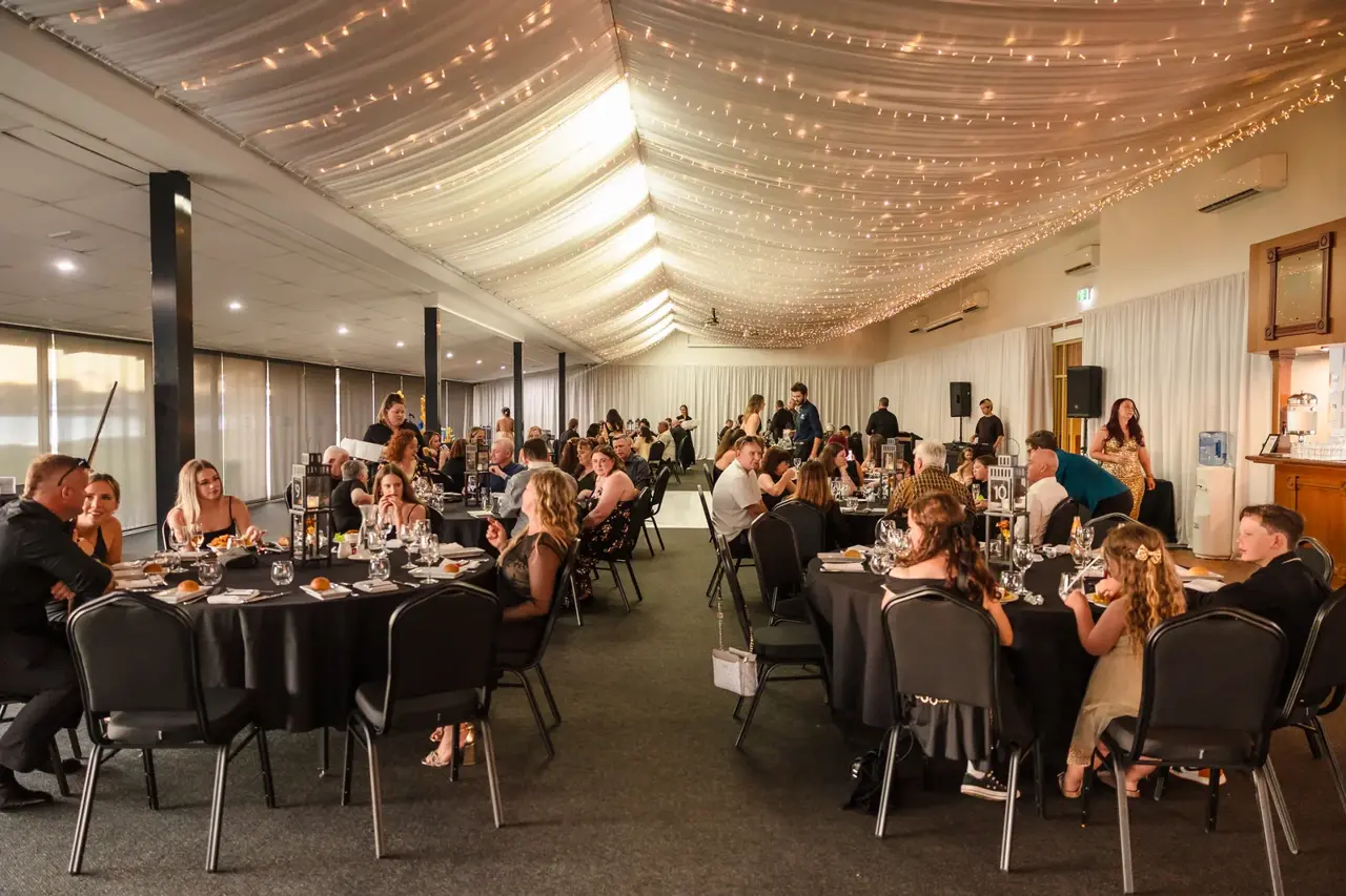 The glass-walled riverside reception room with string lights at Burswood on Swan