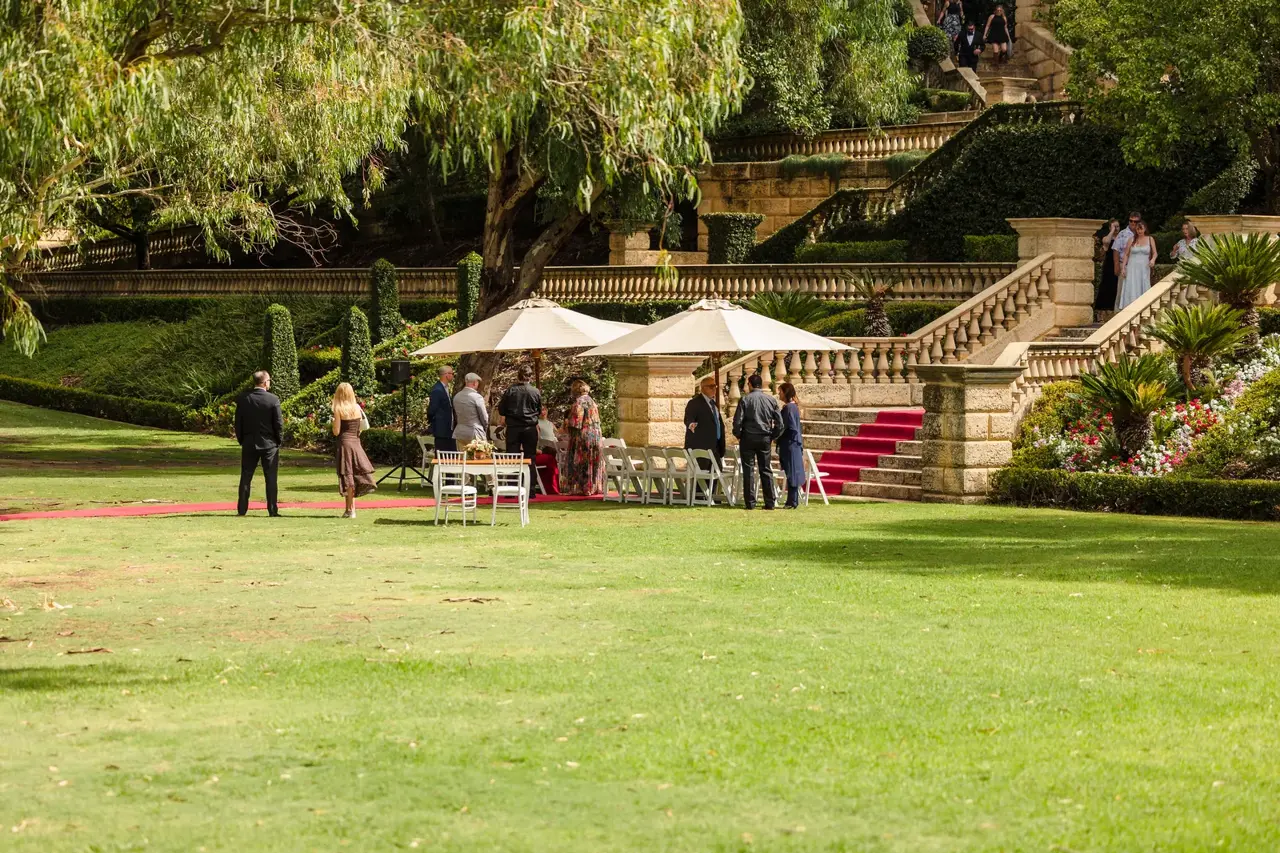The ceremony lawn at Caversham House, a red carpet between white chairs and sunshades with the stone terraces behind