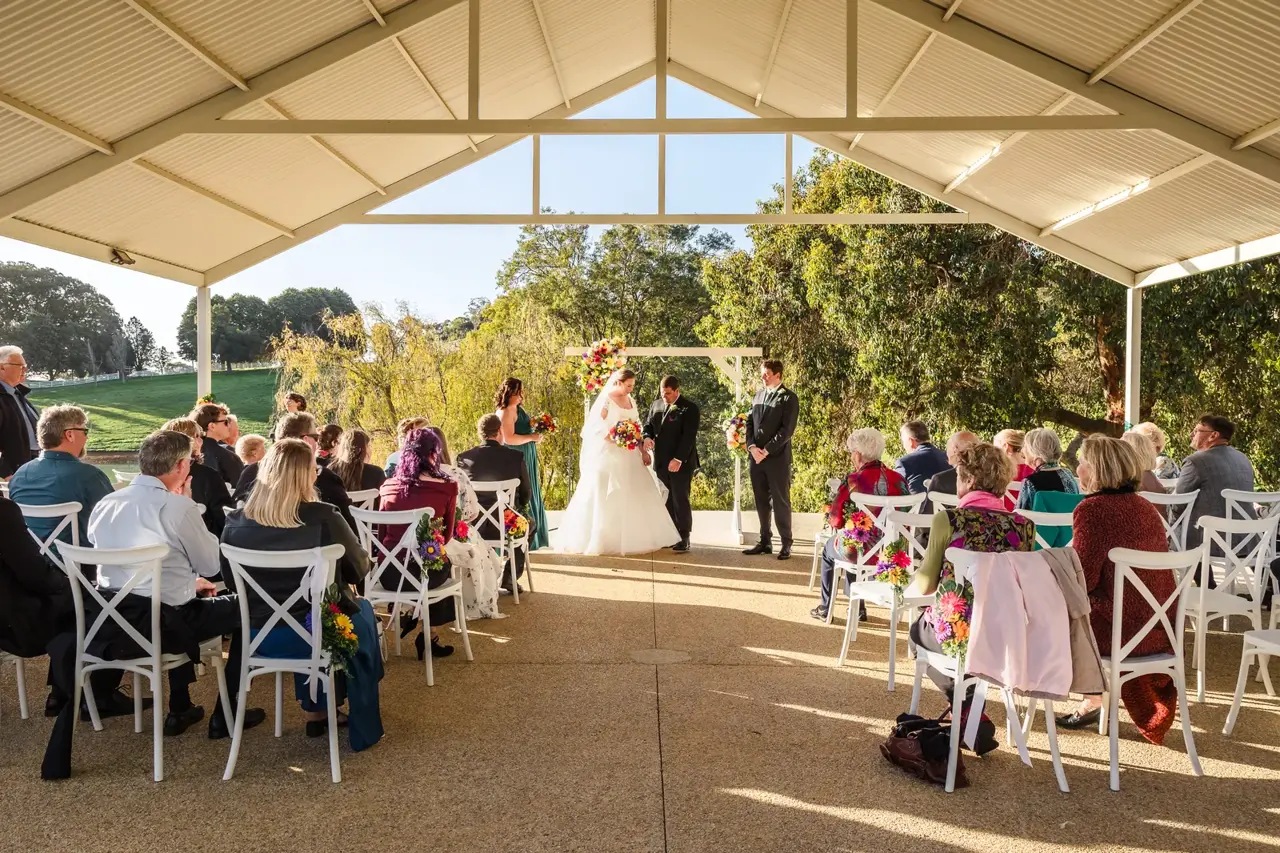 A wedding ceremony under the big gazebo at Quarry Farm with the dam and green hills behind