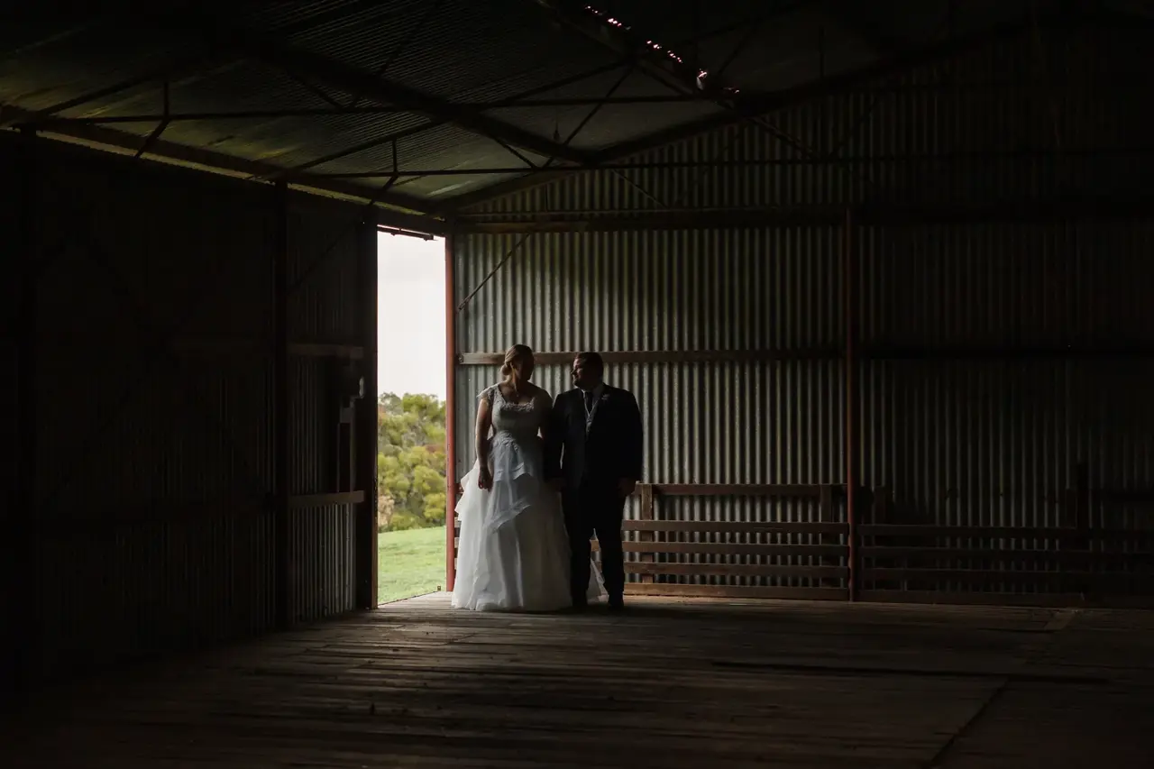 A couple stand together inside the old corrugated-iron shearing shed at Quarry Farm