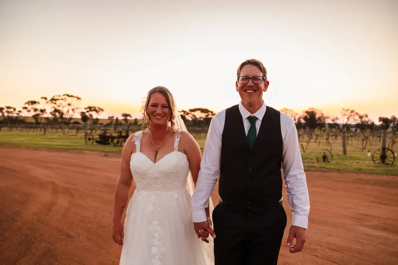 A couple on the red dirt at sunset beside the vines at Walkers Hill Vineyard