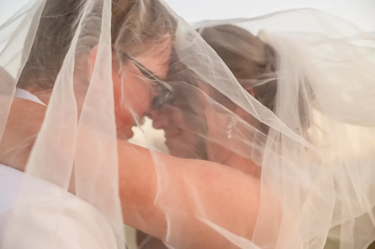 A couple under her veil in the last light at Walkers Hill Vineyard