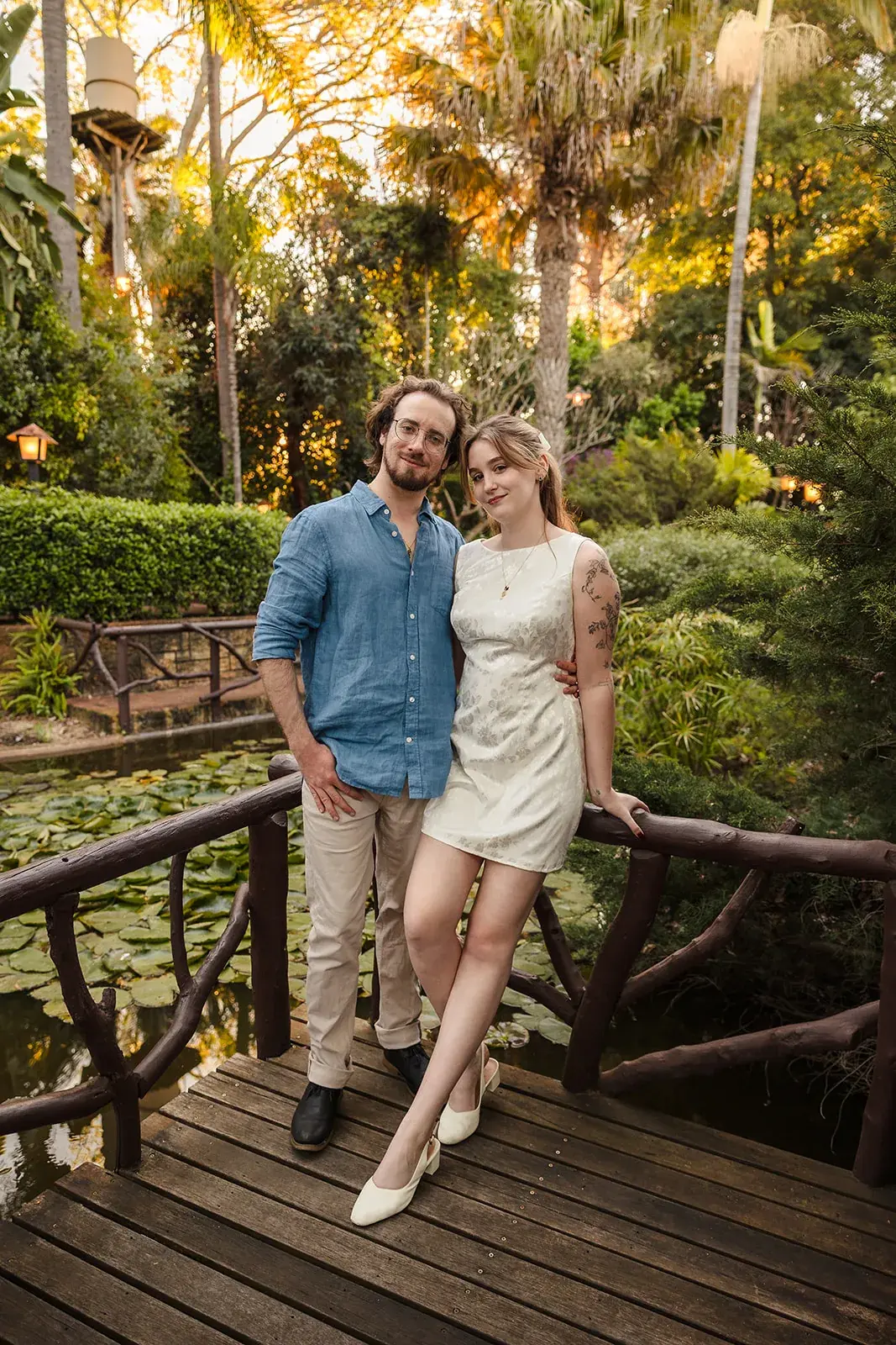 A couple on the ornamental bridge over the lily pond, framed by greenery at Wanneroo Botanic Gardens