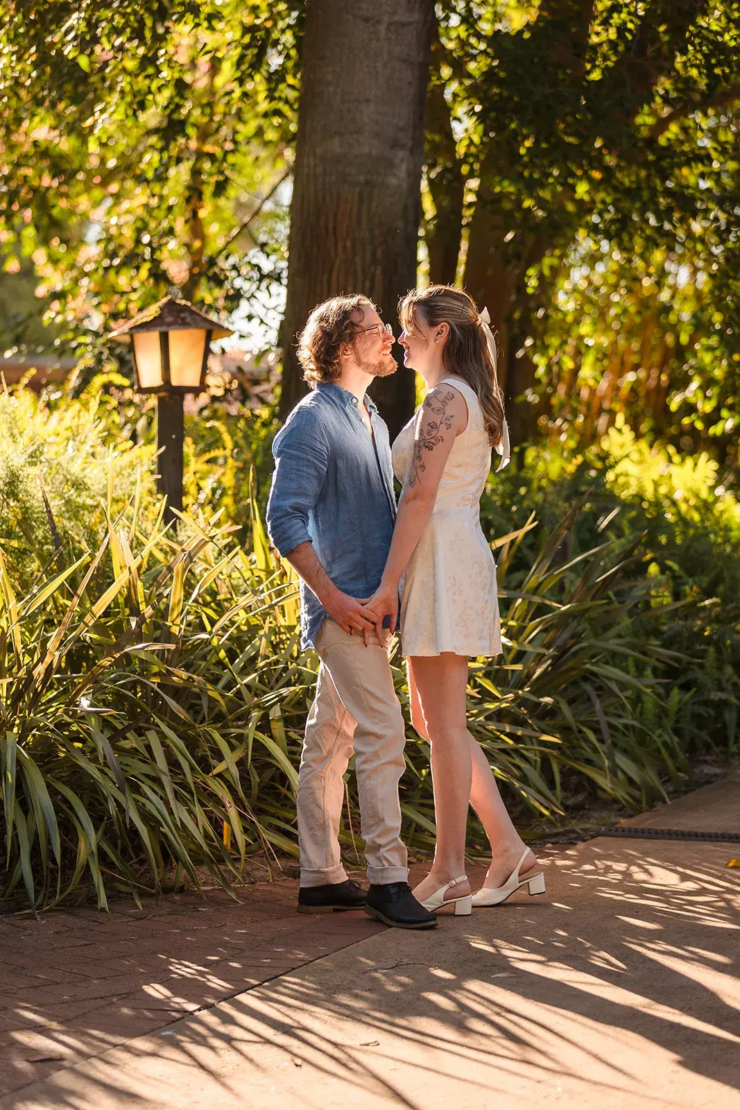 A couple share a golden-hour moment beside a garden lamp post at Wanneroo Botanic Gardens