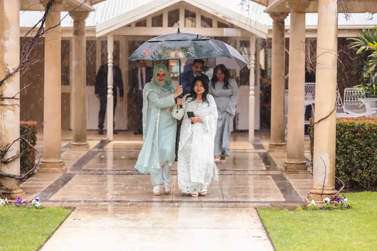 Family members shelter under umbrellas along the rainy colonnade