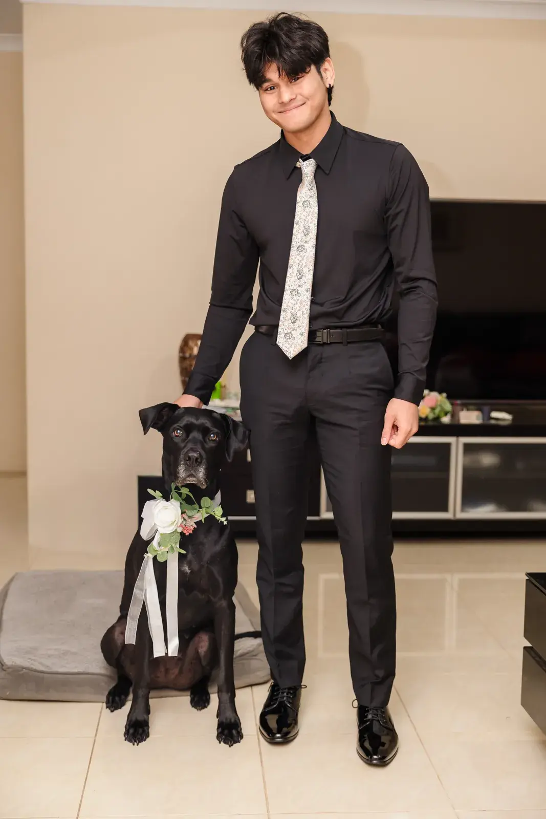 Kusal in a black suit with Luna, who wears a white ribbon on her collar
