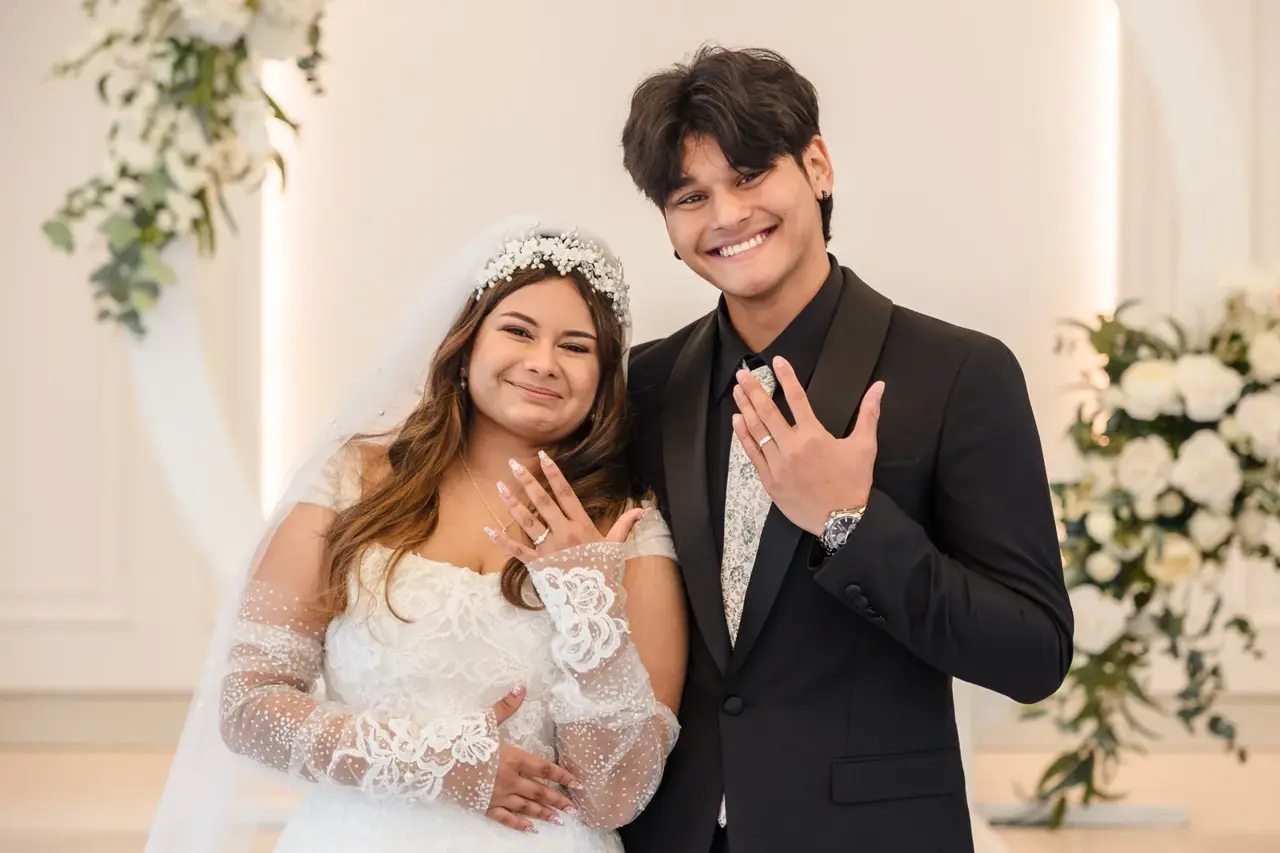 Naila and Kusal hold up their certificate of marriage at the signing table