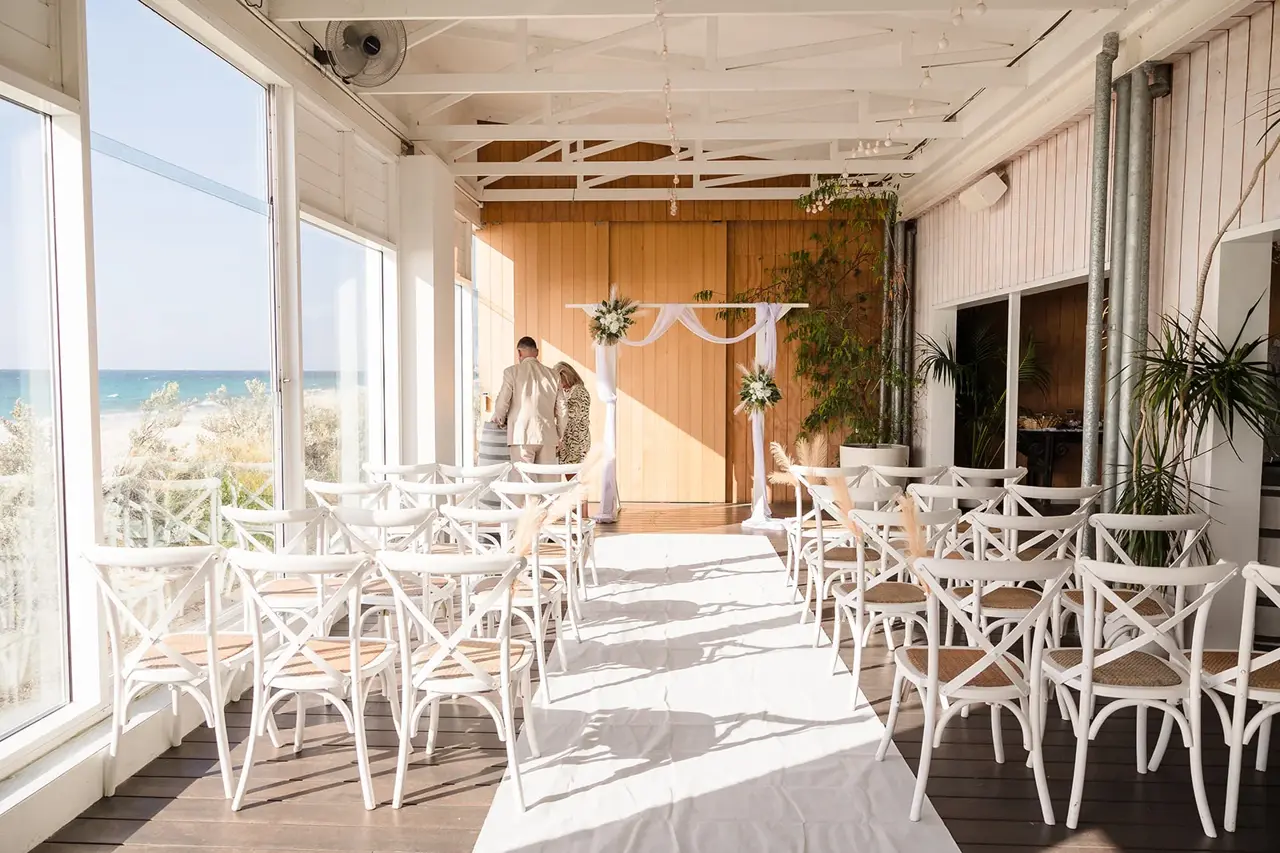 Covered deck with white chairs overlooking the ocean at COAST Port Beach