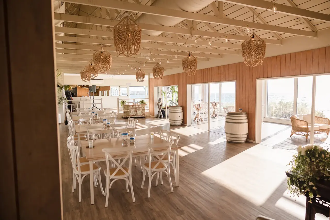 Bright beach-house dining room with white chairs at COAST Port Beach