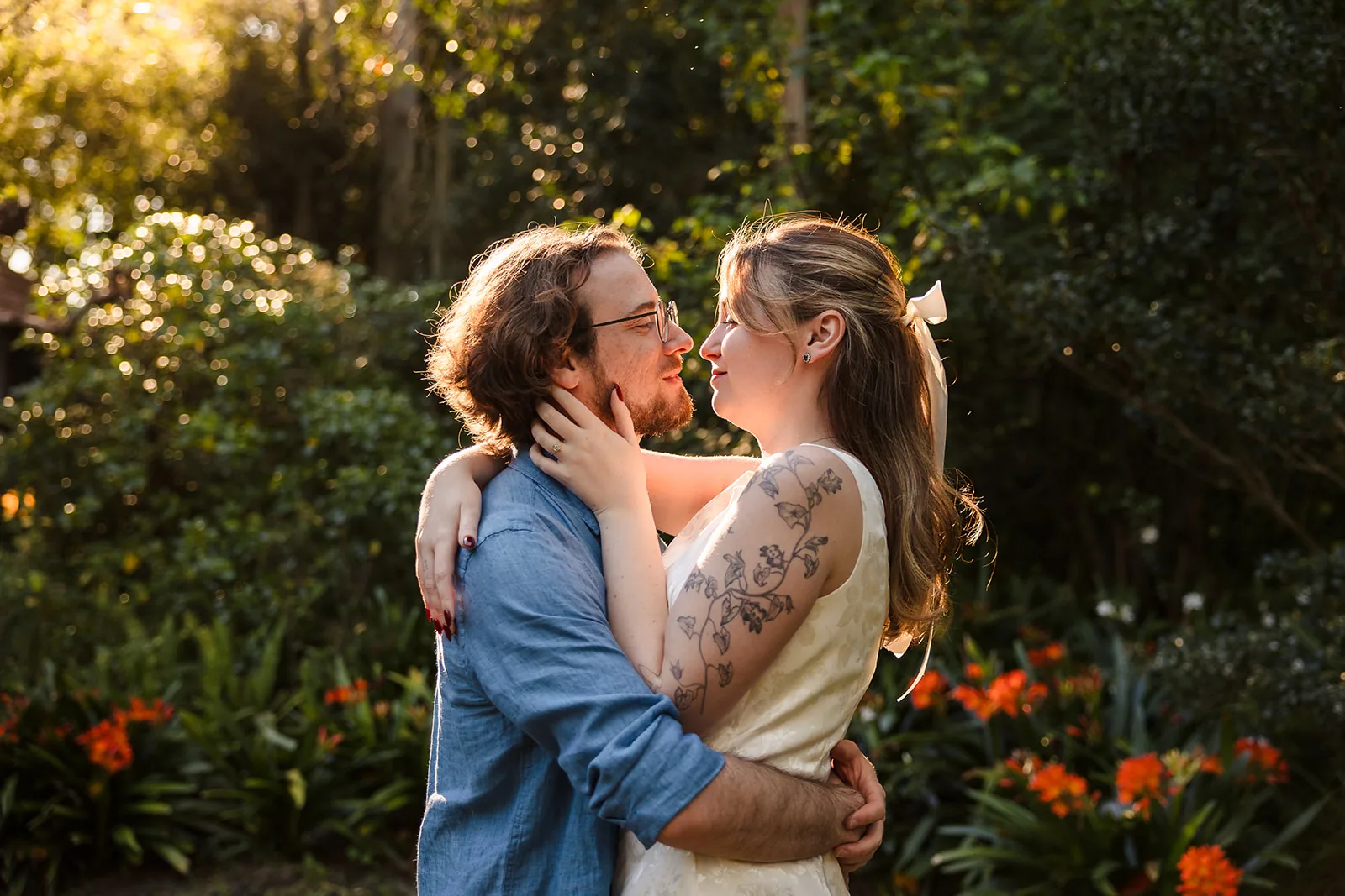 Arden and Kobi in a close embrace among the greenery and orange blooms at Wanneroo Botanic Gardens