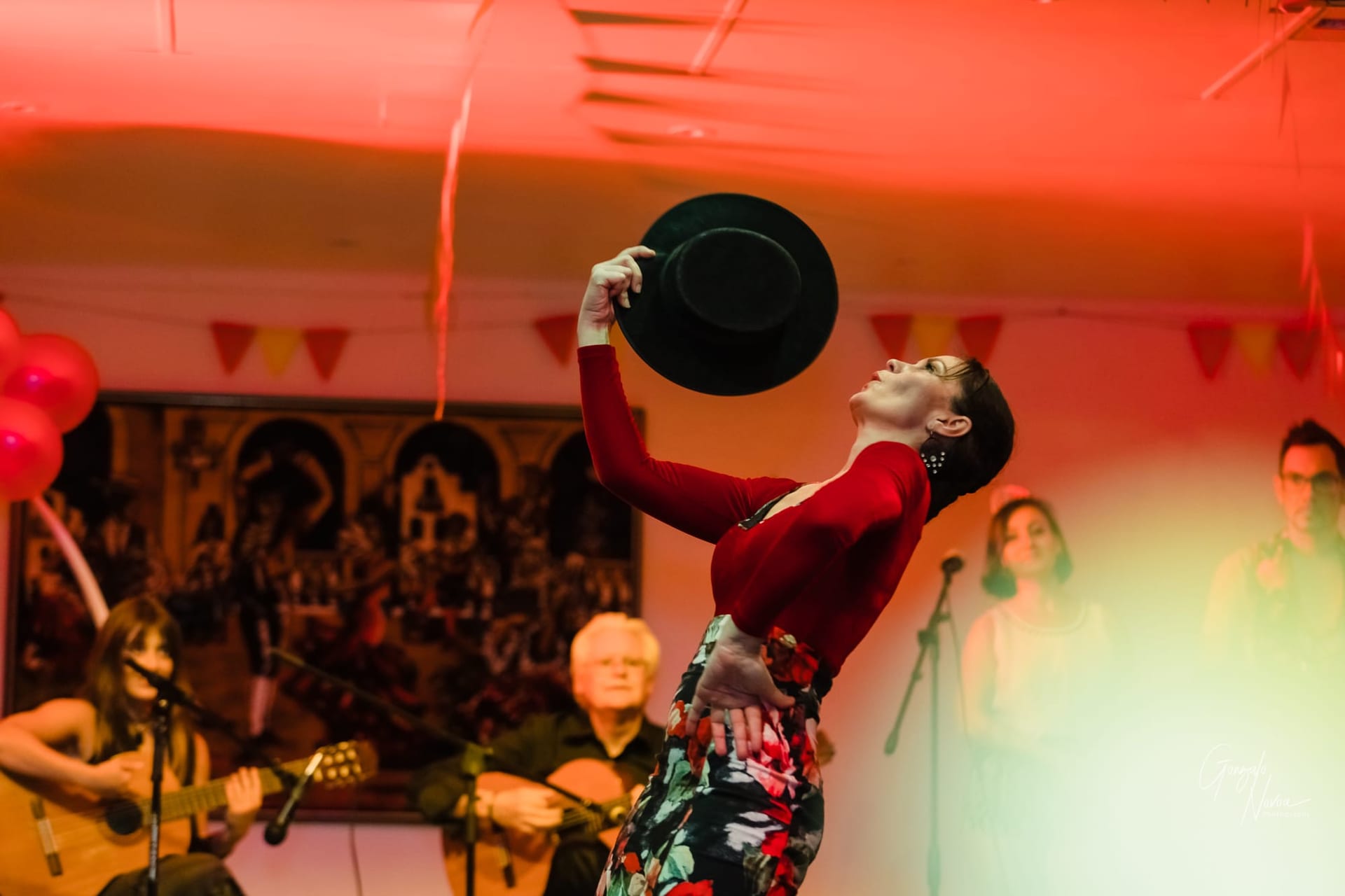 Flamenco dancer, mid performance, back arched fanning herself with her hat