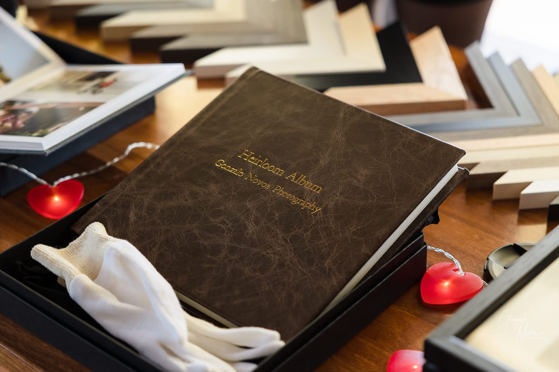 Wedding album with gold engraving over a table, surrounded with frame mouldings for printed artwork