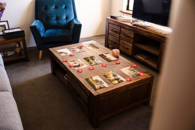 Gonzalo Novoa’s former photography studio in Viveash, features a wooden coffee table with printed wedding photos, red heart lights, and a cosy seating area.