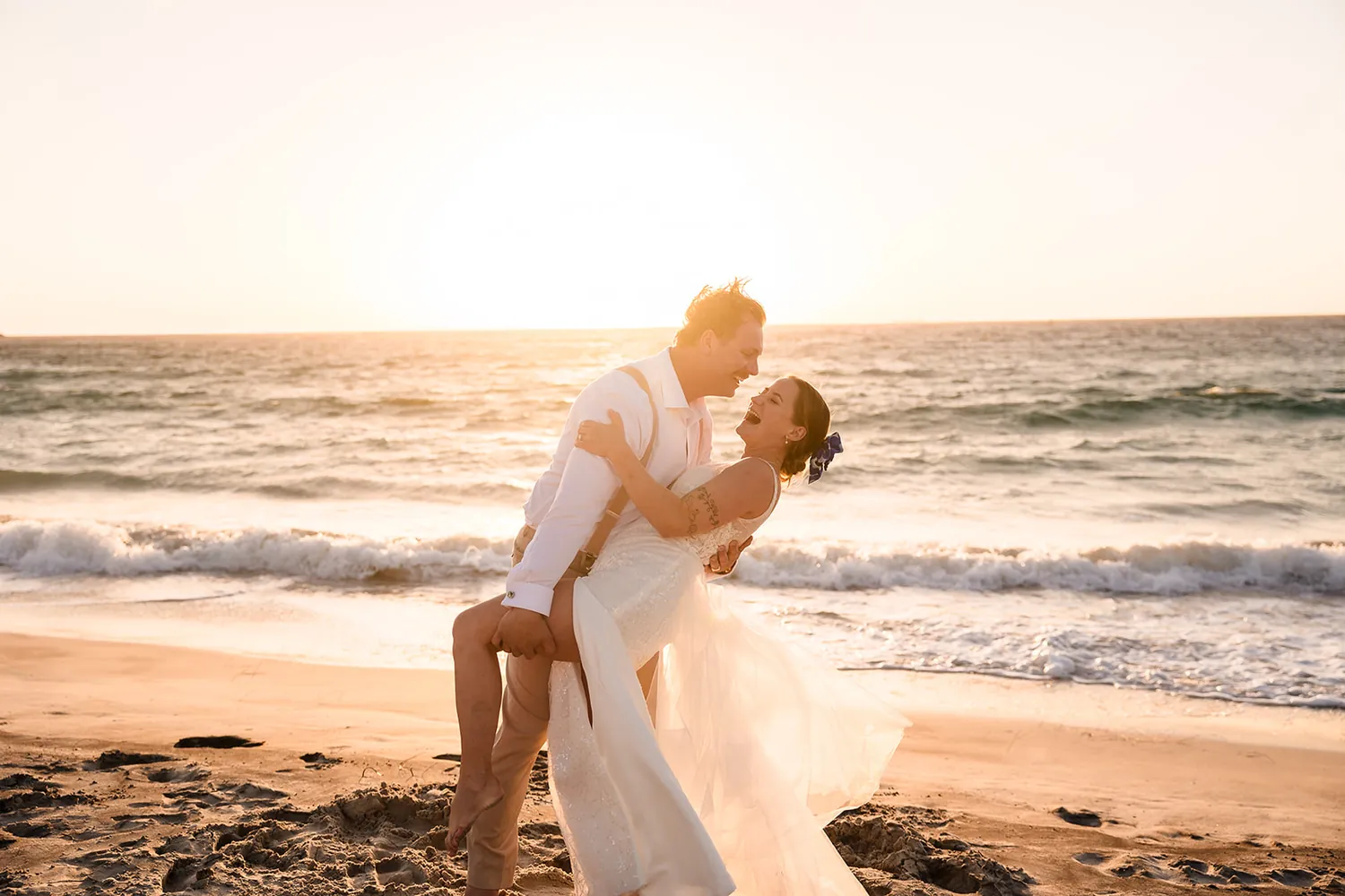 Jaana and Andy dip kiss on the beach at sunset at Port Beach