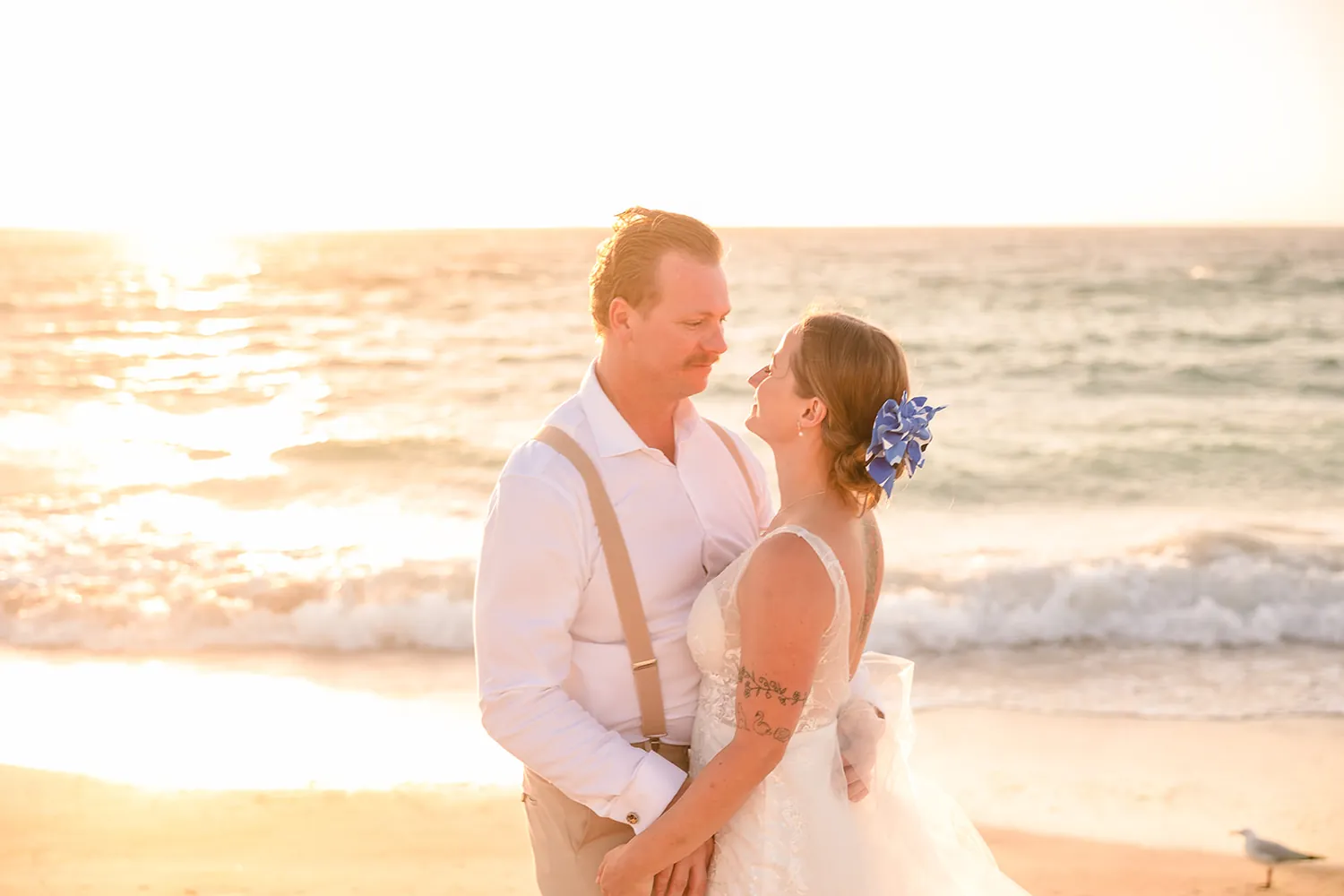 The couple embracing in the golden light on the beach at Port Beach