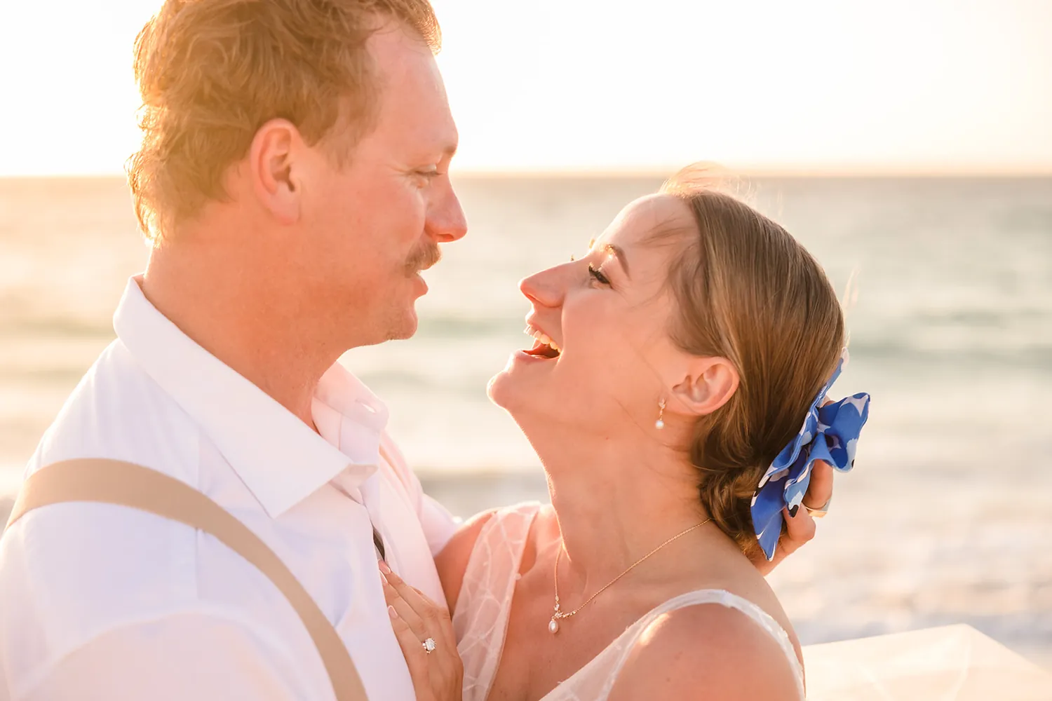 The couple nose to nose on the beach, with a blue Marimekko hairpiece