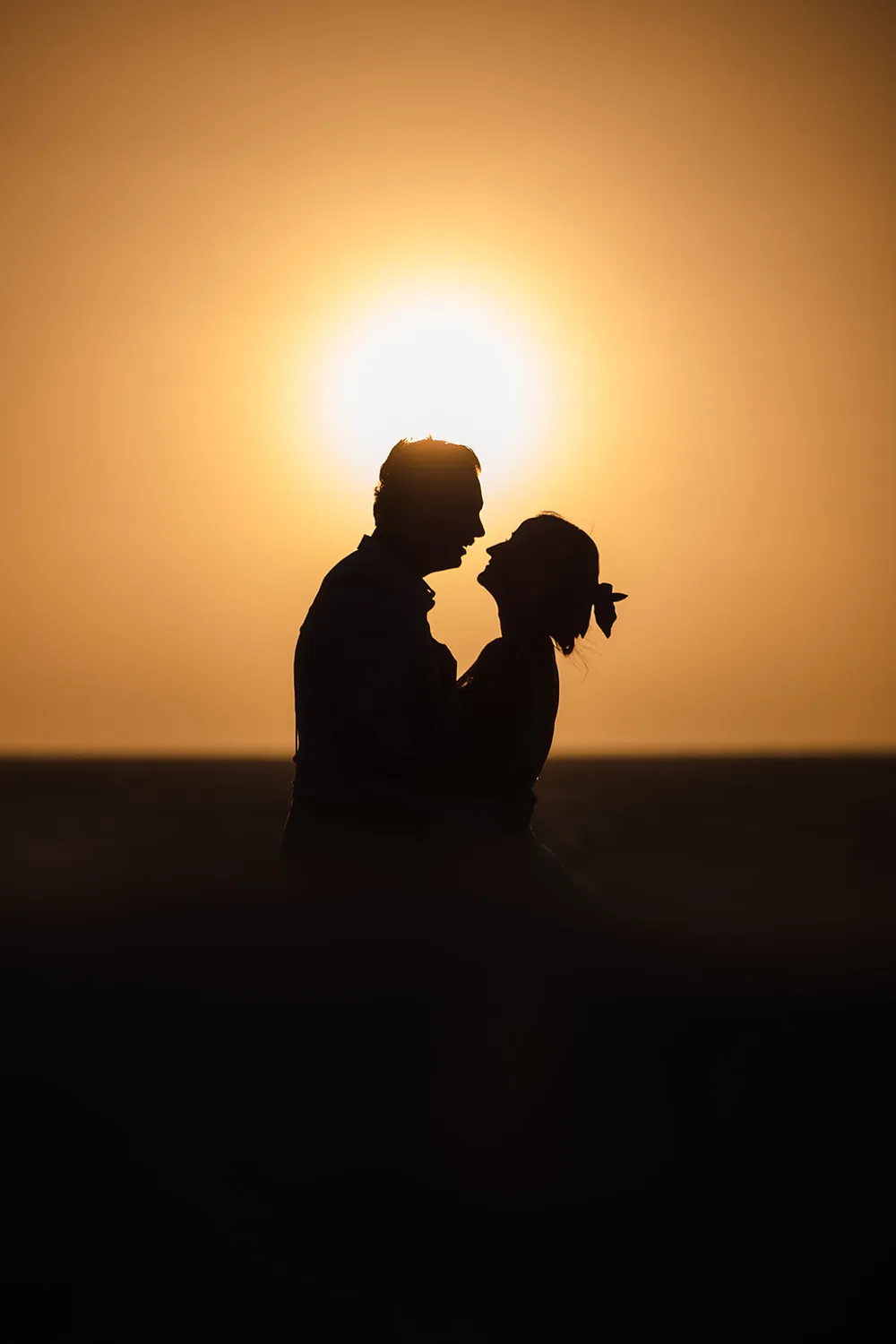 Jaana and Andy silhouetted against the setting sun over the ocean at Port Beach