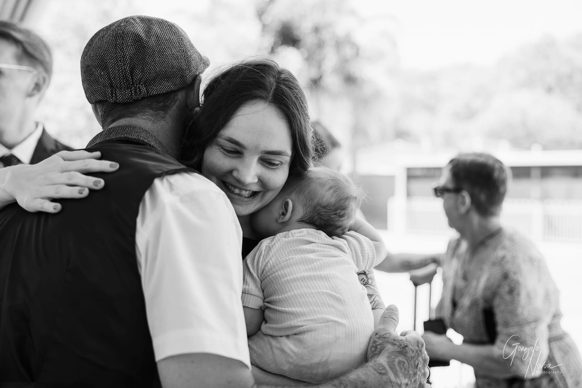 A touching wedding moment as the groom and a guest share a warm hug under soft natural light.
