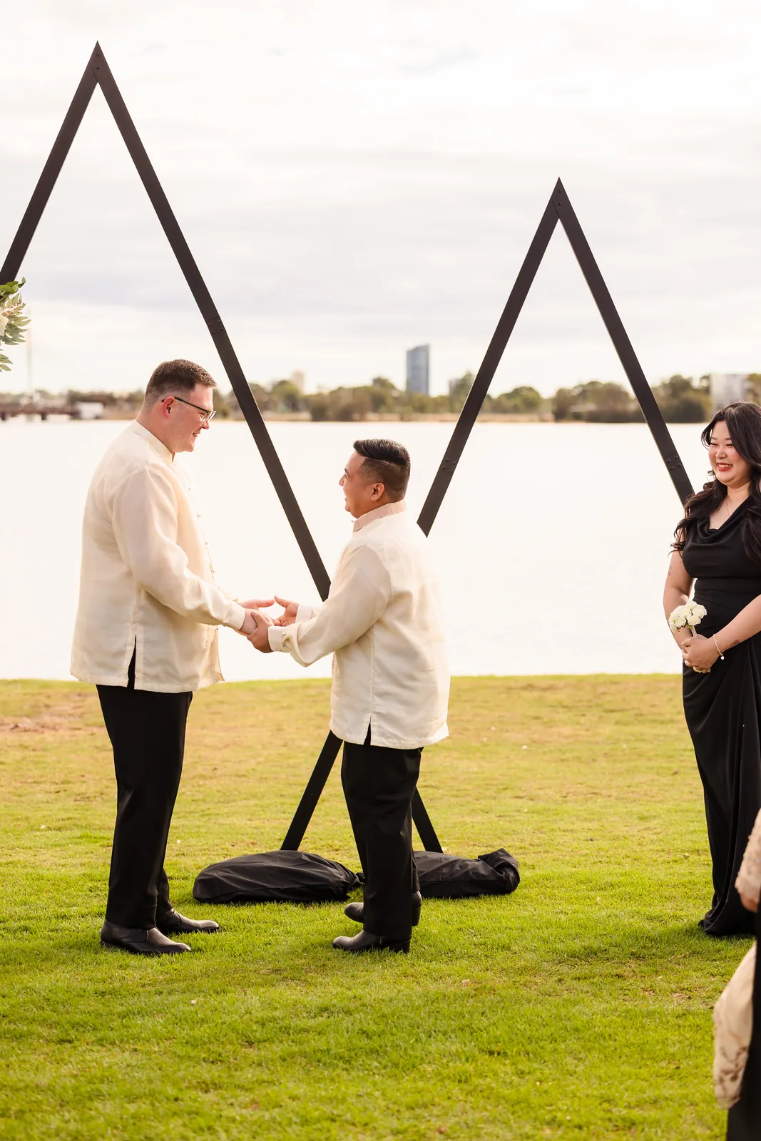Lloyd and Mitch holding hands at the arbour with the Swan River behind at Burswood on Swan