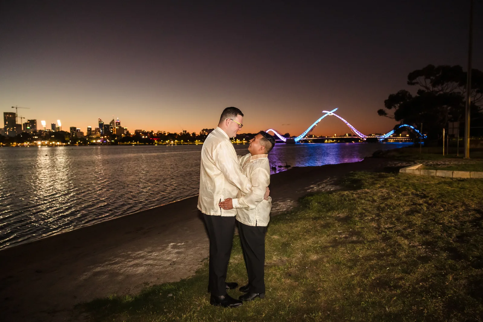 Lloyd and Mitch by the Swan River at night with the lit Matagarup bridge behind at Burswood on Swan