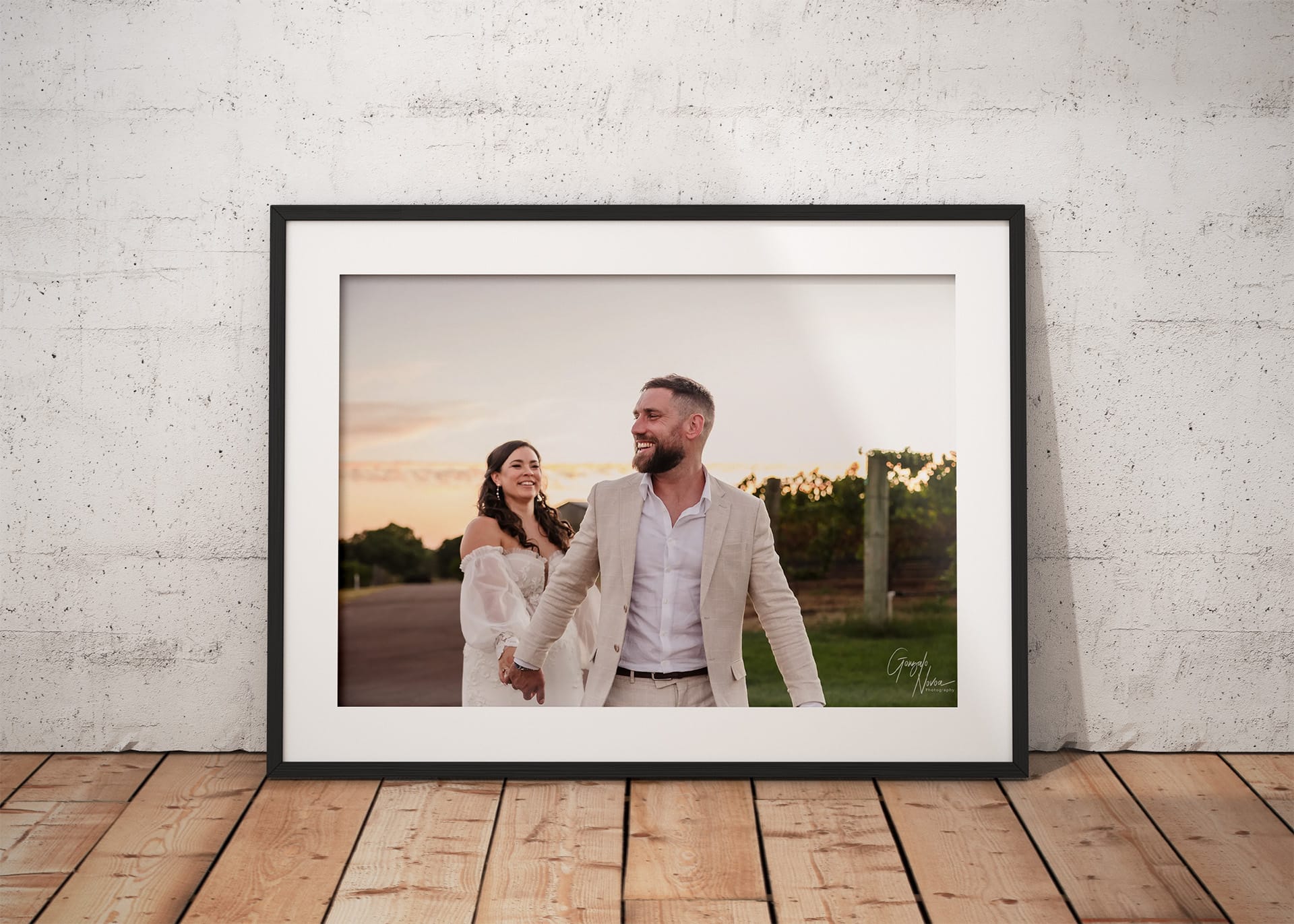 Framed wedding photo of Tahnee and James walking hand-in-hand at sunset near the vines at Sittella Winery. James is smiling ahead while Tahnee gazes at him lovingly, both dressed in light-toned wedding attire, captured during golden hour.