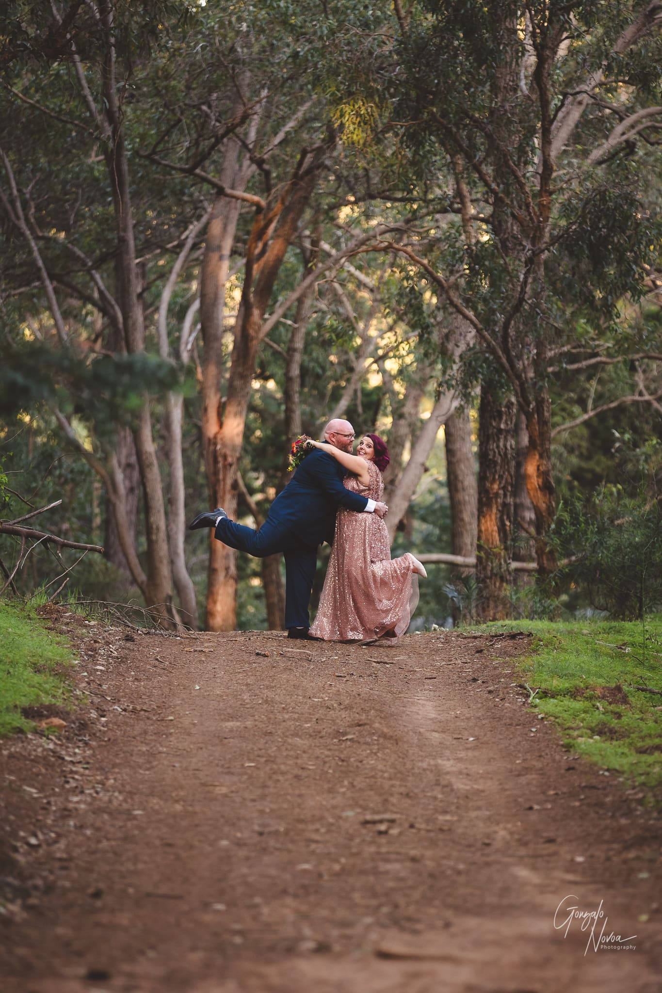 A bride and groom share a tender embrace amidst the serene beauty of the woods. Love blossoms in nature's embrace.