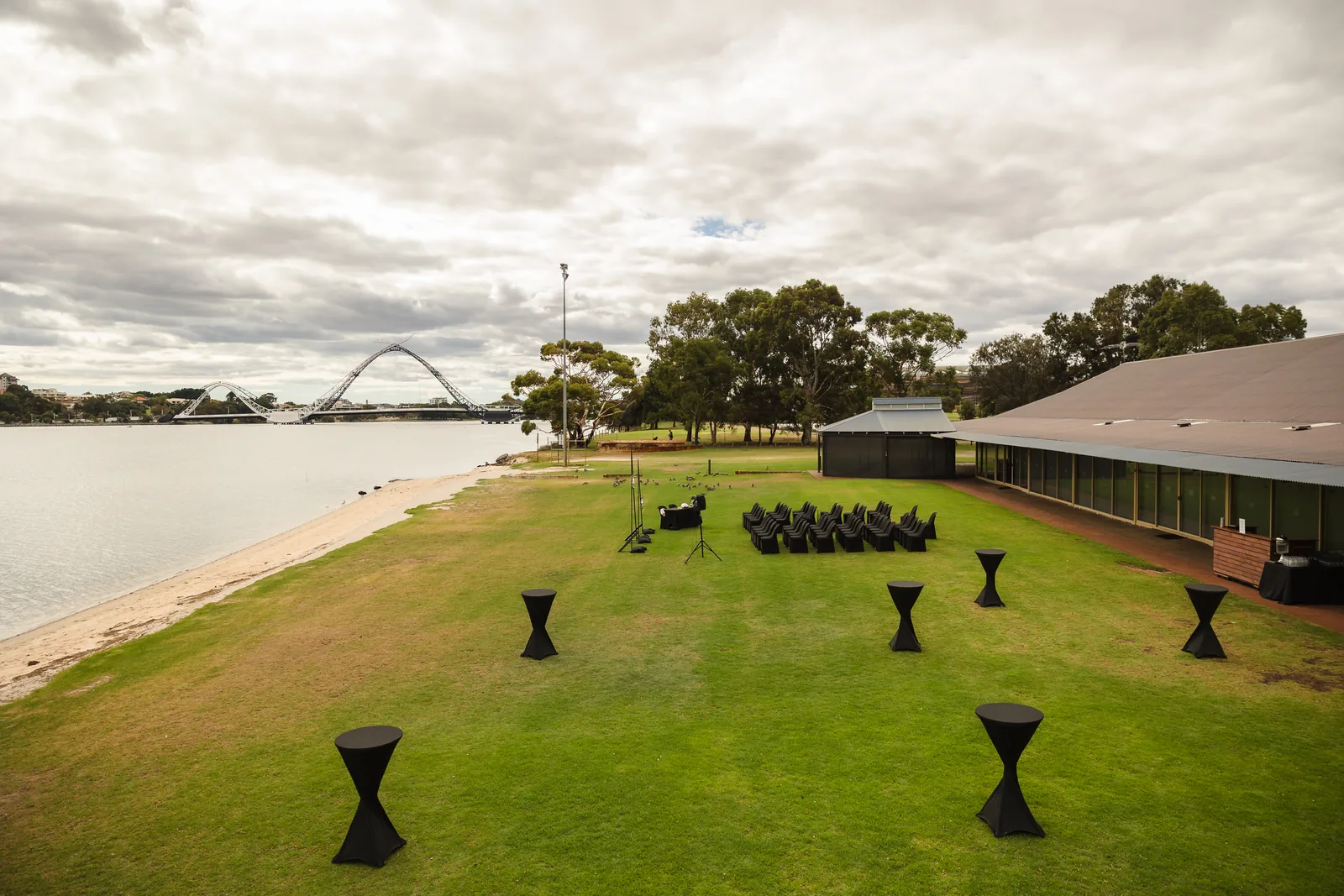 The riverside ceremony lawn and venue building with the Matagarup bridge across the Swan River at Burswood on Swan