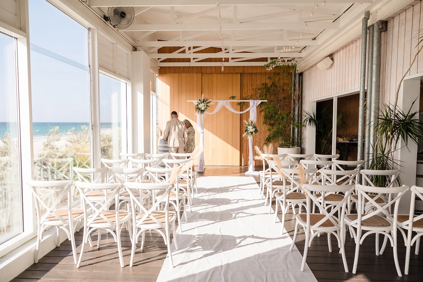 Covered deck with white chairs overlooking the ocean at COAST Port Beach